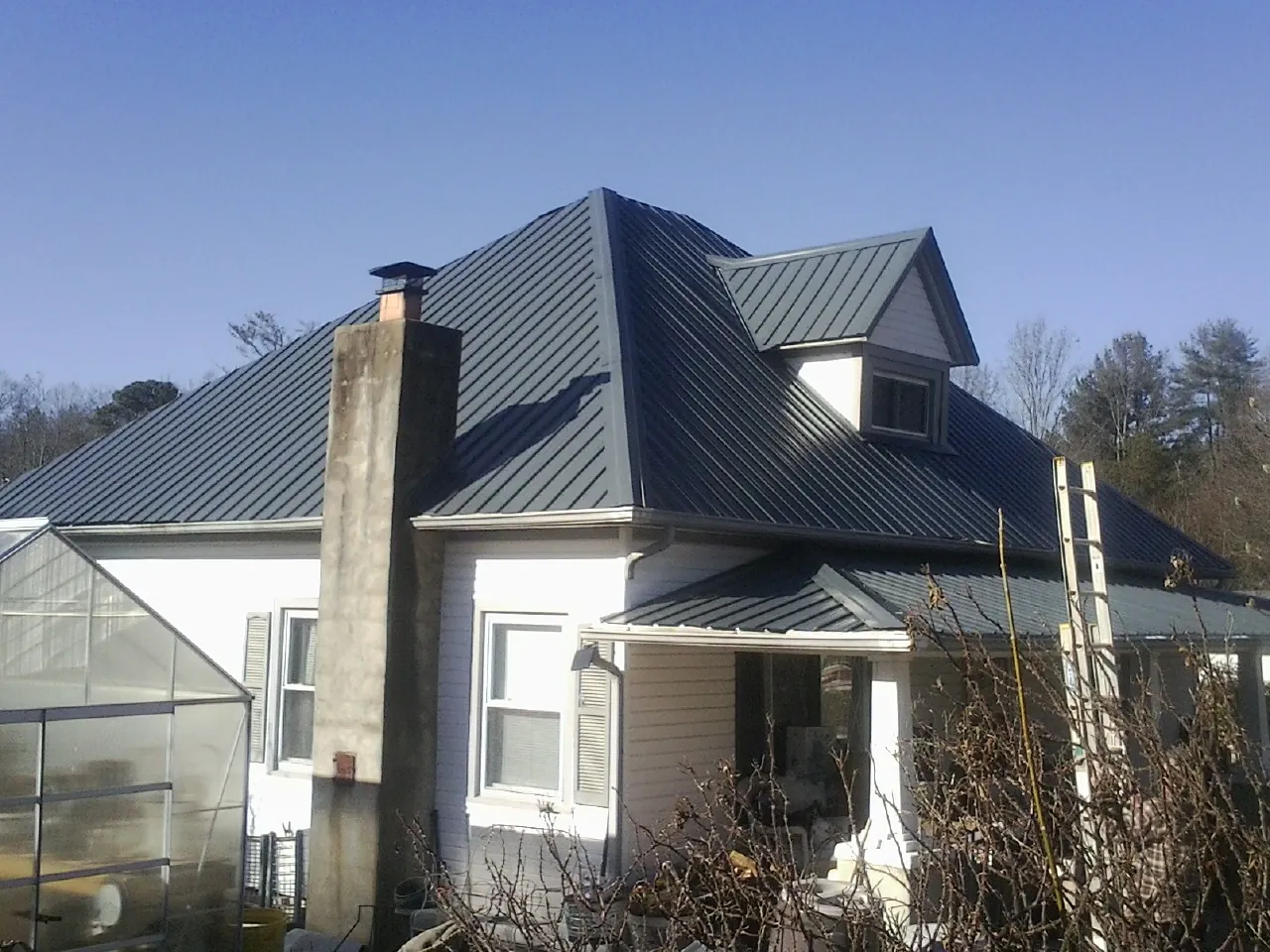 Dark blue standing seam metal roof on a white farmhouse with dormer — Slate & Tile Roof Repair by Roofing Brothers in Redkey