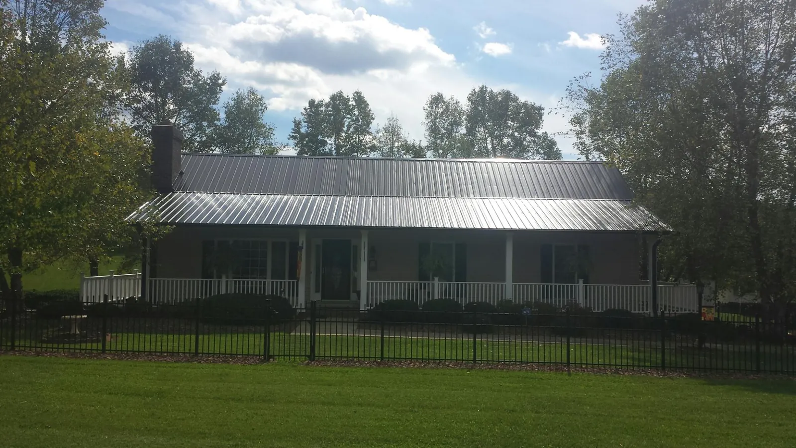 Gray metal roof on a brick ranch with a full width front porch — Gutter Guard Installation work by our crew in Redkey